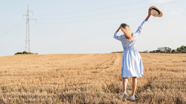 Lange Schuss blonde Frau, die die Natur in einem Feld mit Kopienraum genießt