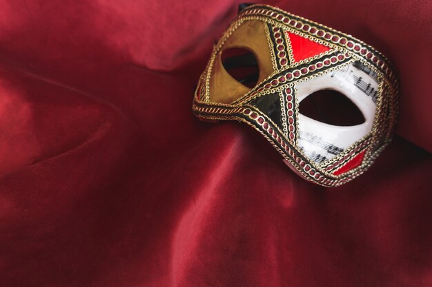 Lange venezianische Maske auf einem roten Stoff