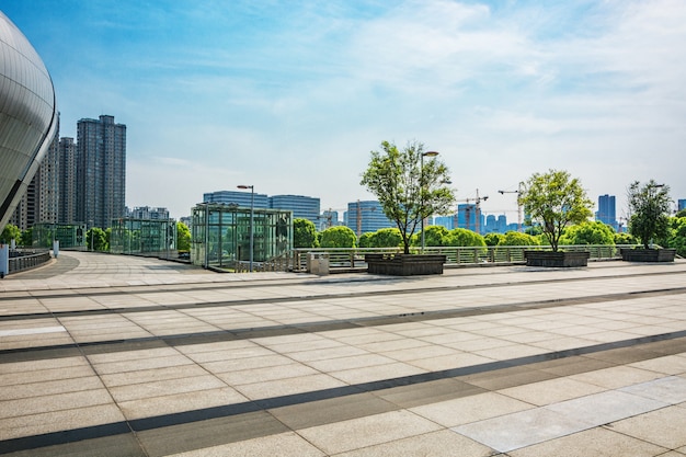 Langer leerer Fußweg im modernen Stadtplatz mit Skyline.