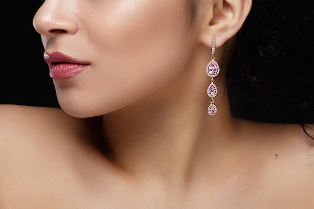 Langer Ohrring mit violetten Edelsteinen hängt am Ohr der Frau