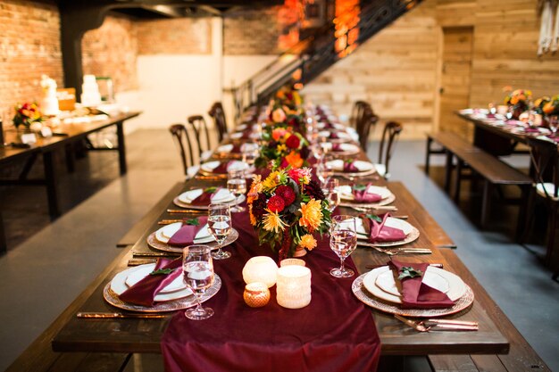 Langer Tisch mit Luxusplatten und dekoriert mit bunten Blumen und Kerzen
