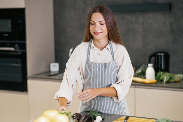 Langhaarige junge Frau, die das Mittagessen in der Küche zubereitet