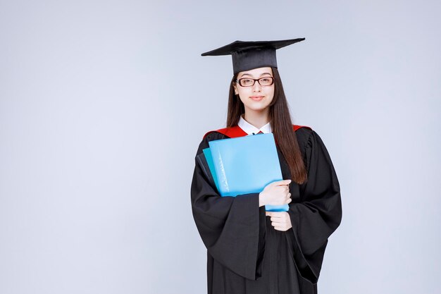 Langhaariger Student mit Brille, der auf blaue Ordner zeigt. Foto in hoher Qualität