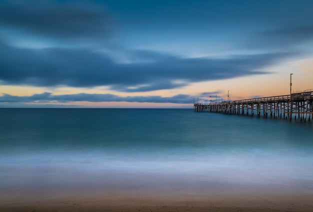 Langzeitbelichtung eines hölzernen Piers im Meer in Kalifornien am Abend