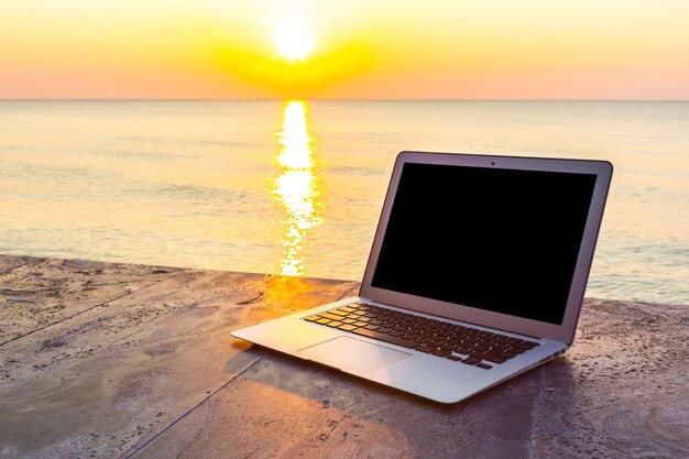 Laptop auf Steinoberfläche und Meer Hintergrund