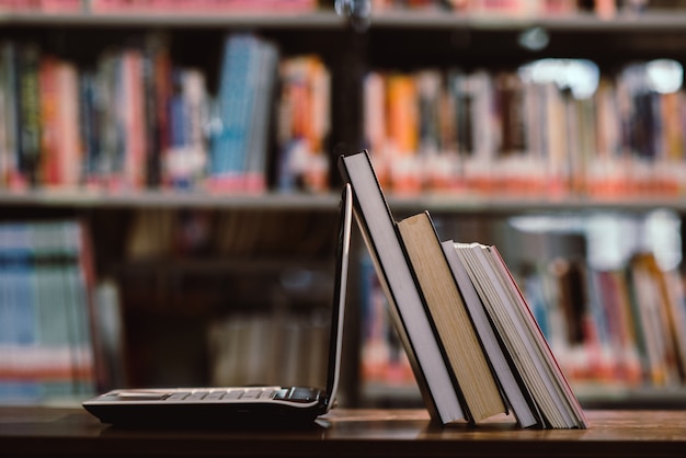 Kostenloses Foto laptop-computer und buch am arbeitsplatz im bibliotheksraum