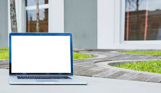 Laptop mit leerem Bildschirm vor Haus