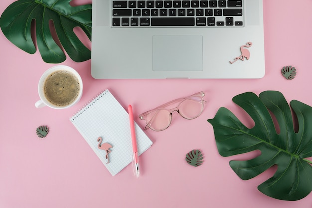 Laptop mit Notizbuch und kleinen Flamingos auf Tabelle