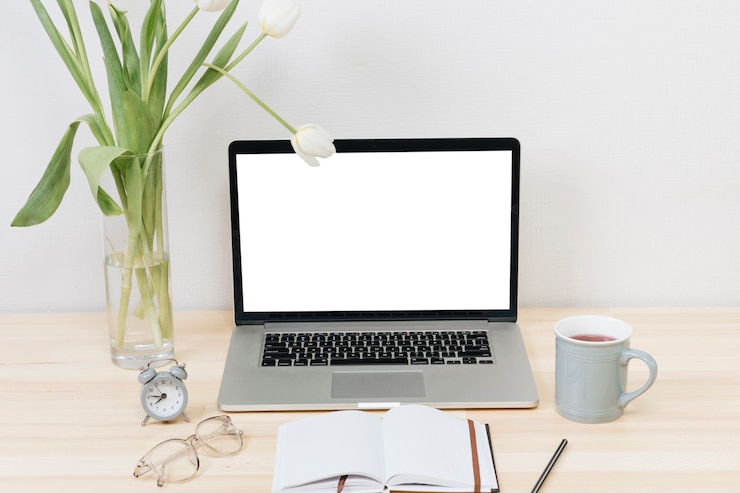 Kostenlose Foto laptop mit weißen tulpen im vase auf holztisch