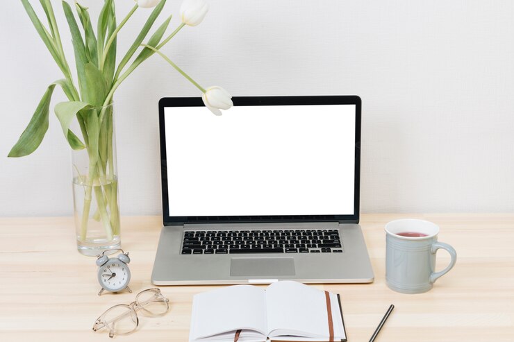 Kostenlose Foto laptop mit weißen tulpen in einer vase auf einem holztisch