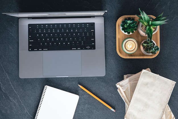 Laptop-Notizbuch und Bücher von oben auf dunklem Hintergrund