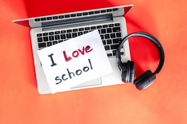 Laptop und Kopfhörer auf rotem Hintergrund lieben das Schulkonzept