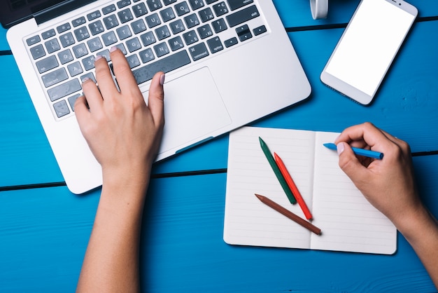 Laptop und Notizbuch auf blauem Schreibtisch