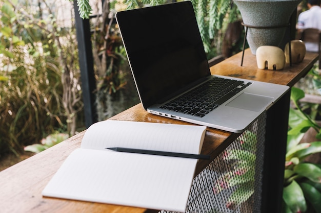 Laptop und Notizbuch im Garten