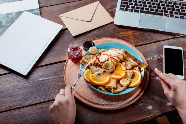 Laptop und Pfannkuchen mit Saft. Gesundes Frühstück