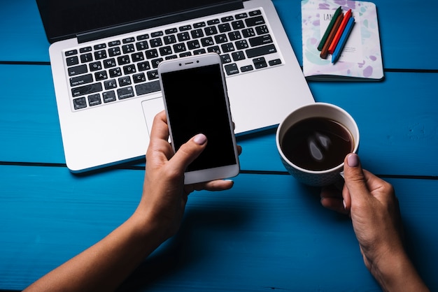 Laptop und Smartphone auf blauem Schreibtisch mit Kaffee