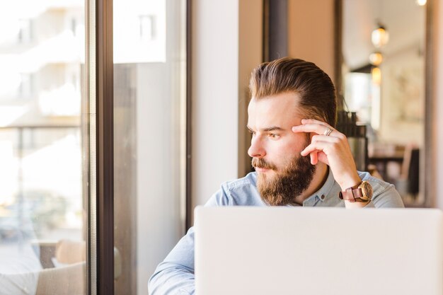 Laptop vor dem jungen Mann, der im Café sitzt