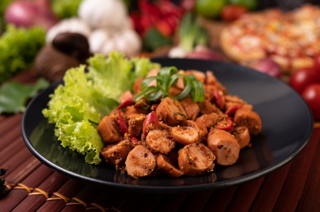 Larb Wurst mit Chili Frühlingszwiebeln und Salat in einem schwarzen Teller