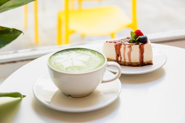 Lattekunst mit japanischem matcha und Käsekuchen des grünen Tees auf weißer Tabelle