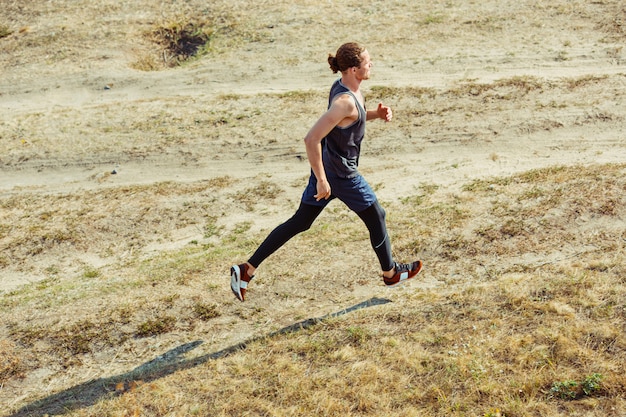 Laufsport. Mannläufer, der im Freien in der landschaftlich reizvollen Natur sprintet. Fit muskulöses männliches Athleten-Trainings-Trailrunning für den Marathonlauf. Sportlich fit sportlicher Mann, der im Sprint in Kompressionskleidung trainiert