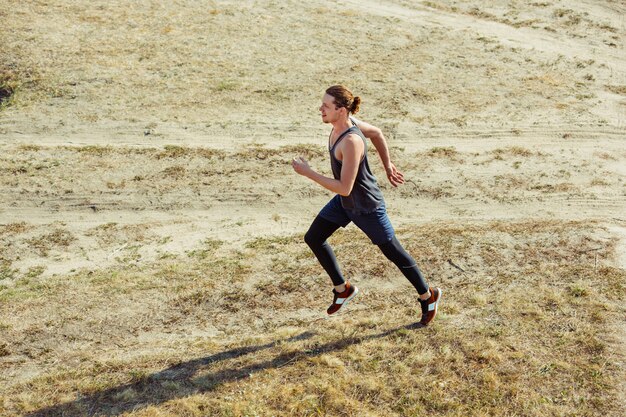 Laufsport. Mannläufer, der im Freien in der landschaftlich reizvollen Natur sprintet.