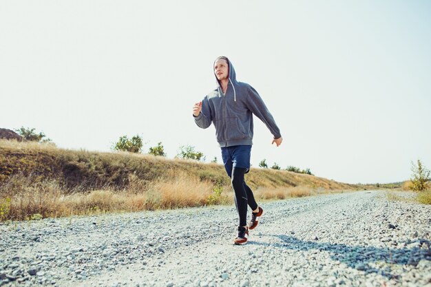 Laufsport. Mannläufer, der im Freien in der landschaftlich reizvollen Natur sprintet.