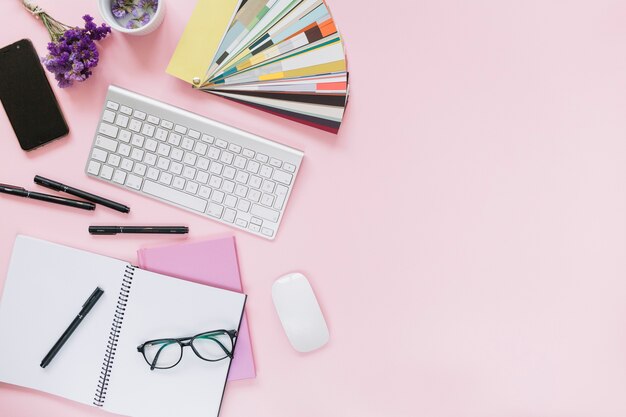 Lavendel; Handy; Tastatur und Maus mit Büromaterial auf farbigen rosa Hintergrund