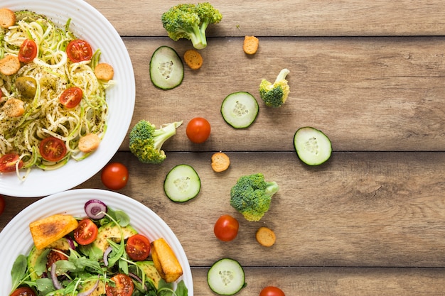 Lebensmittel des strengen Vegetariers auf weißen Platten mit hölzernem Hintergrund