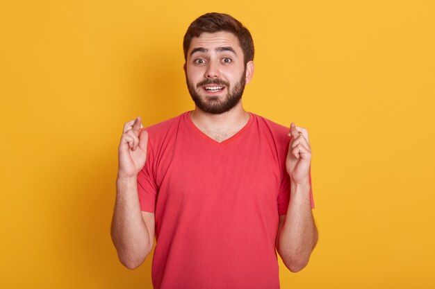 Lebensstil und Menschenkonzept. Bild og attraktiver Kerl, der auf besonderen Moment wartet, junger bärtiger Mann, der rotes lässiges T-Shirt trägt