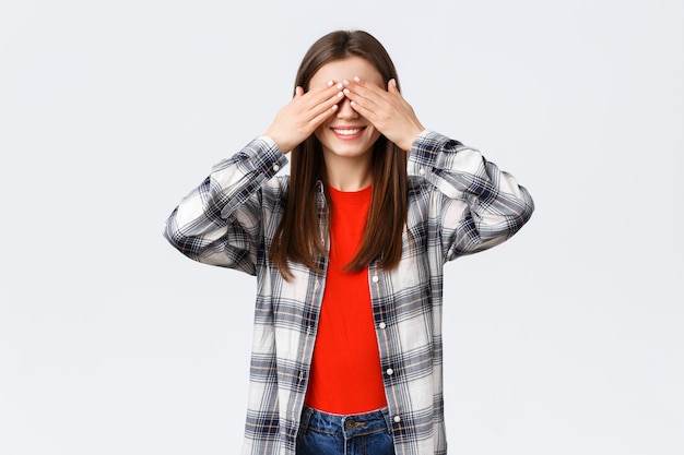 Lebensstil, verschiedene Emotionen, Freizeitkonzept. Aufgeregtes glückliches junges entspanntes Mädchen verspricht keinen Blick. Frauen bedecken die Augen mit Handflächen, spielen Verstecken oder warten auf Überraschung.