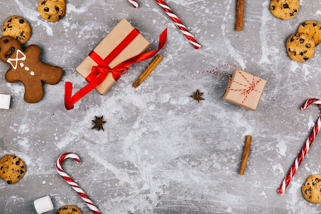 Lebkuchen, Kekse, Marshmallows, rote weiße Knödel, Zimt, andere Gewürze liegen auf dem Boden um den Präsentkarton herum