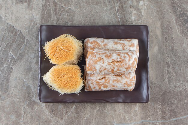 Lebkuchen mit Marmelade in Zuckerglasur und Kadayif auf Platte auf Marmor.