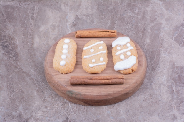 Lebkuchen-Weihnachtsplätzchen mit Zimtstangen auf rundem Holzbrett.