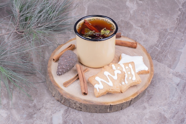 Lebkuchenplätzchen in Sternform mit einer Tasse Kräutertee und Zimt.