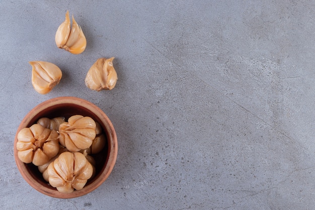 Lecker eingelegter Knoblauch in der Schüssel auf Steintisch.