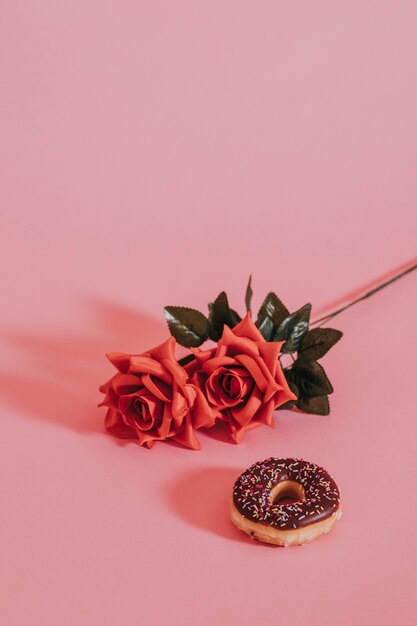 Lecker glasierter Donut neben einer Rose