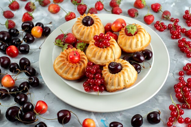 Lecker Kuchen der Vorderansicht mit milden und saftigen roten Früchten innerhalb des weißen Beerenfruchtkuchens