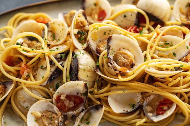 Leckere appetitliche frische hausgemachte Muscheln alle vongole Meeresfrüchteteigwaren mit Knoblauch und Weißwein auf Teller. Nahansicht.