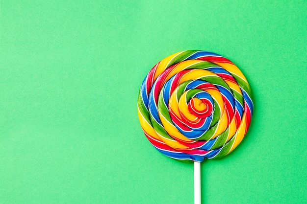 Leckere appetitliche Party Zubehör Sweet Swirl Süßigkeiten Lollypop auf grünem Hintergrund Draufsicht