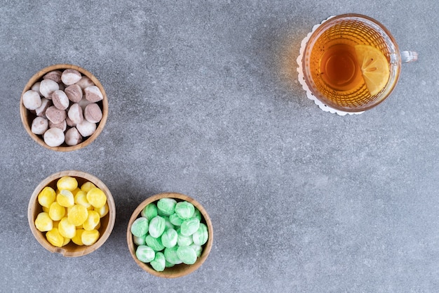 Leckere Bonbons und eine Tasse Tee mit Zitronenscheibe auf Marmoroberfläche