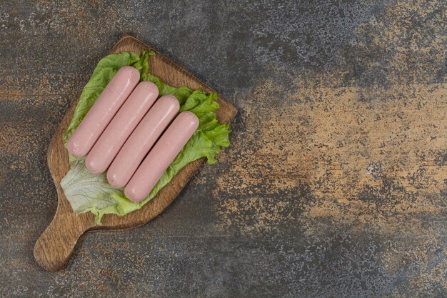 Leckere Brühwürste und Salat auf Holzbrett.