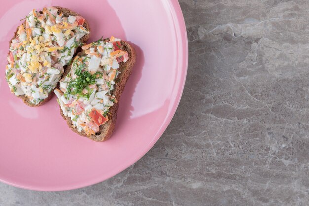 Leckere Bruschetta mit Gemüse auf rosa Teller.