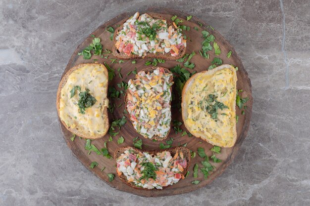 Leckere Bruschettas mit Eiern und Gemüse auf Holzstück.