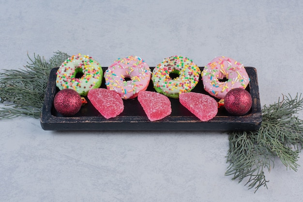 Kostenloses Foto leckere donuts mit sprinklern und marmeladen auf schwarzem teller.