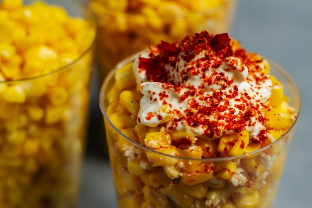 Leckere Esquites mit Gewürzen in Tassen