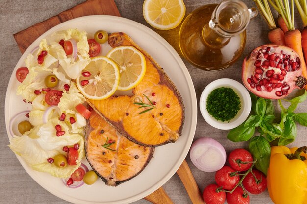 Leckere gekochte Lachsfischfilets. Gegrilltes Lachsfischfilet und frischer grüner Salatgemüsetomatensalat. Ausgewogenes Ernährungskonzept für eine saubere, flexible mediterrane Ernährung.