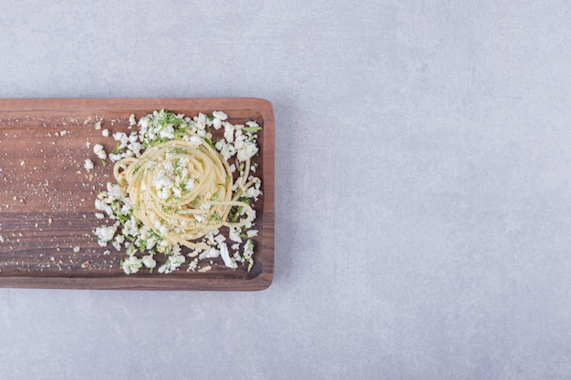 Leckere gekochte Spaghetti mit geriebenem Käse auf Holzbrett.