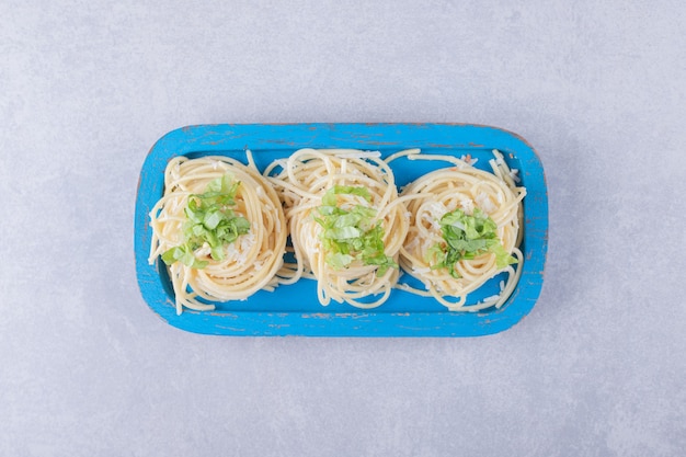 Leckere gekochte Spaghetti mit Grün auf blauem Teller.