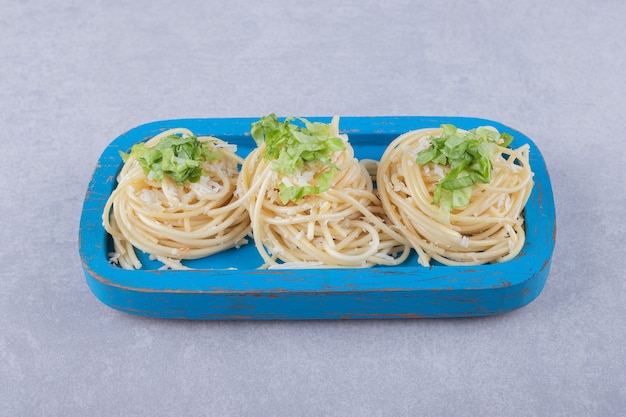 Leckere gekochte Spaghetti mit Grün auf blauem Teller.