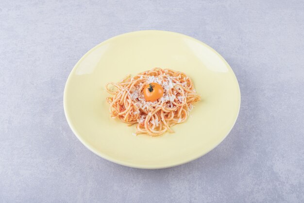 Leckere gekochte Spaghetti mit Tomaten auf gelbem Teller.